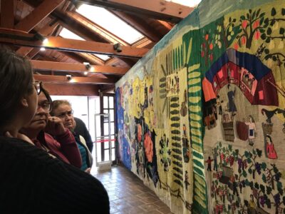 The Collective Embroidery Vecinos, bordadoras y familiares observando el Bordado Colectivo durante su primera exposición en el Museo Casa de Pablo Neruda en Isla Negra