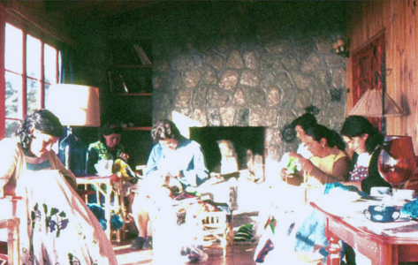 The Collective Embroidery Grupo de seis mujeres bordando el Bordado Colectivo en la galería de Leonor bajo el sol de la tarde en Isla Negra