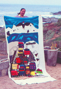 The Collective Embroidery Bordadora de Isla Negra sonriendo con su sección del Bordado Colectivo y el mar de fondo