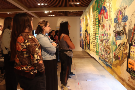 The Collective Embroidery Visitantes del Museo Baburizza observando los detalles técnicos y la materialidad del Bordado Colectivo de Isla Negra