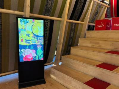 The Collective Embroidery Pantalla vertical de alta definición exhibiendo el registro audiovisual del Bordado Colectivo de Isla Negra en la feria internacional de Osaka